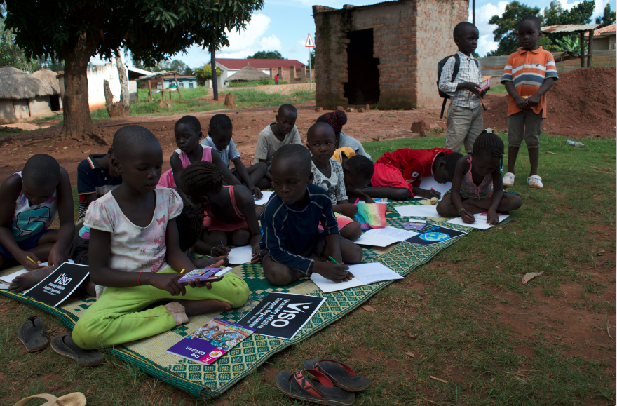 A group of women in Northern Uganda collaboratively processing agricultural products, smiling with a sense of purpose and community.